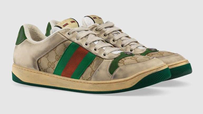 Pár obnošeně vypadajících tenisek Gucci v béžové barvě se zeleným a červeným pruhem