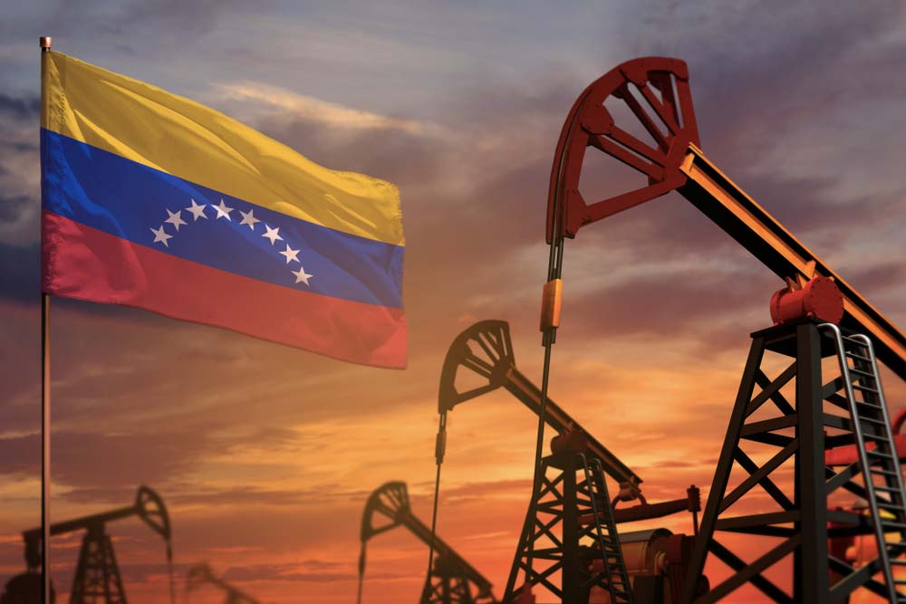 Venezuelská vlajka vedle ropných čerpadel při západu slunce