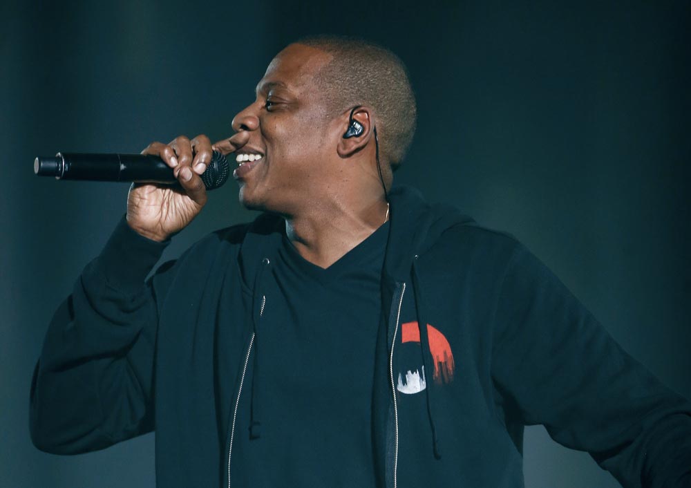 Zpěvák Jay-Z s mikrofonem během koncertu v tmavé mikině