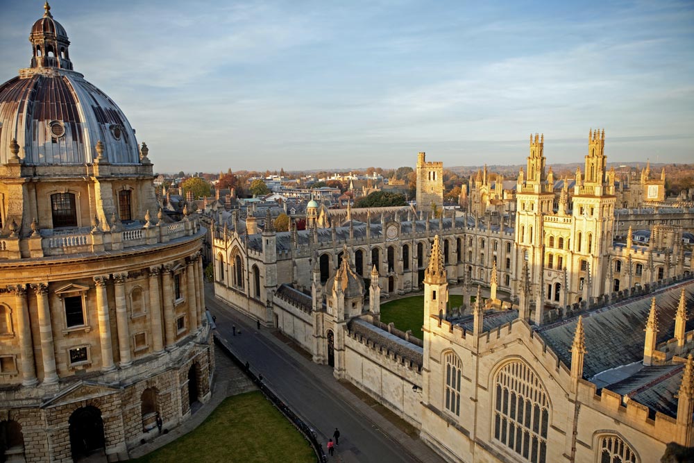 Kopule Radcliffe Camera a věže All Souls College na univerzitě v Oxfordu při západu slunce