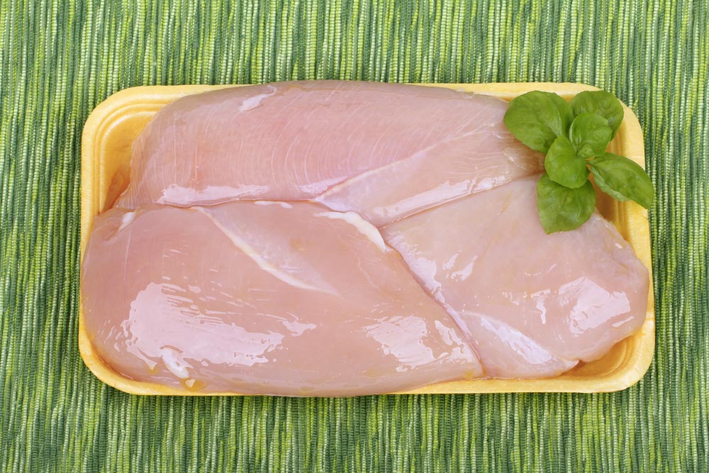 Syrová kuřecí prsa na žlutém tácku s lístky bazalky na zeleném prostírání