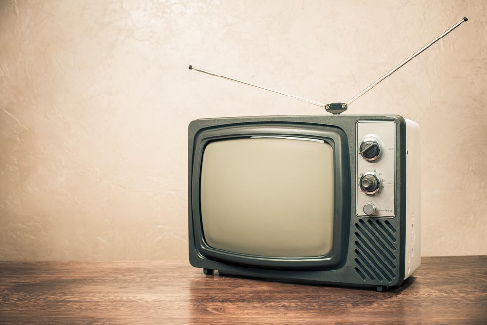 Retro televize s anténními tykadly na dřevěném stole