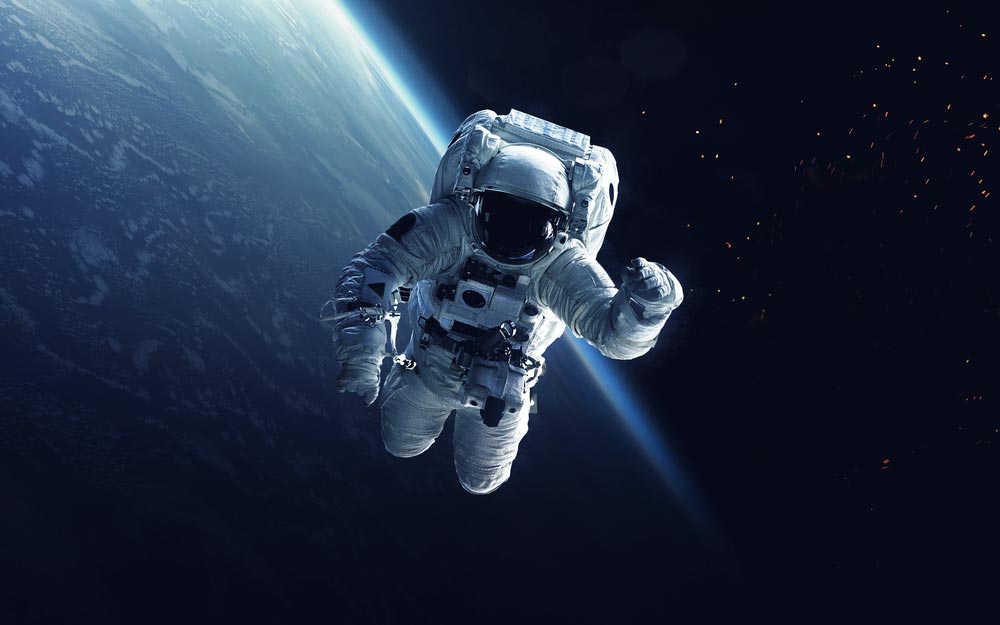 Astronaut ve skafandru vznášející se ve vesmíru nad zeměkoulí