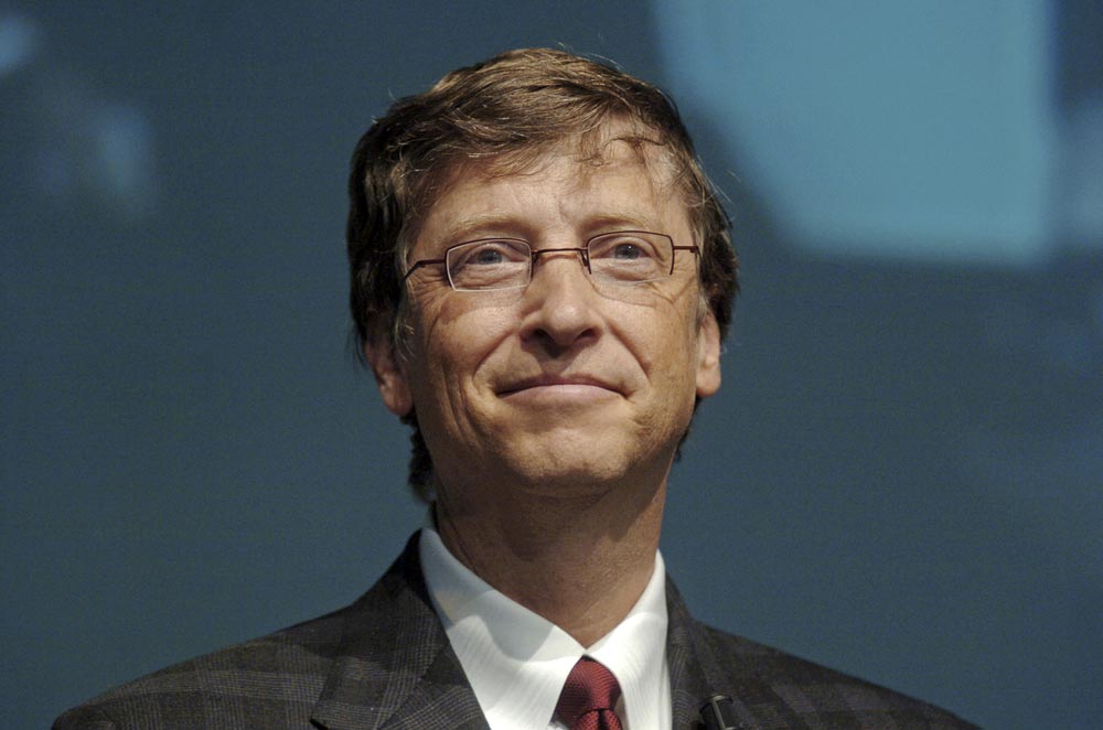 Bill Gates v obleku a brýlích na pódiu