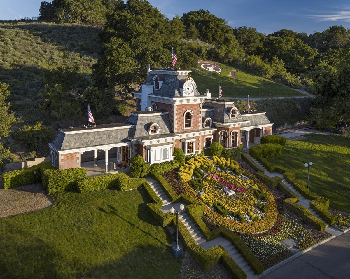 Leteck pohled na sidlo ranče Neverland s vezickovymi hodinami a napisem NEVERLAND vytvarovanym z zivych plotu a kvetin