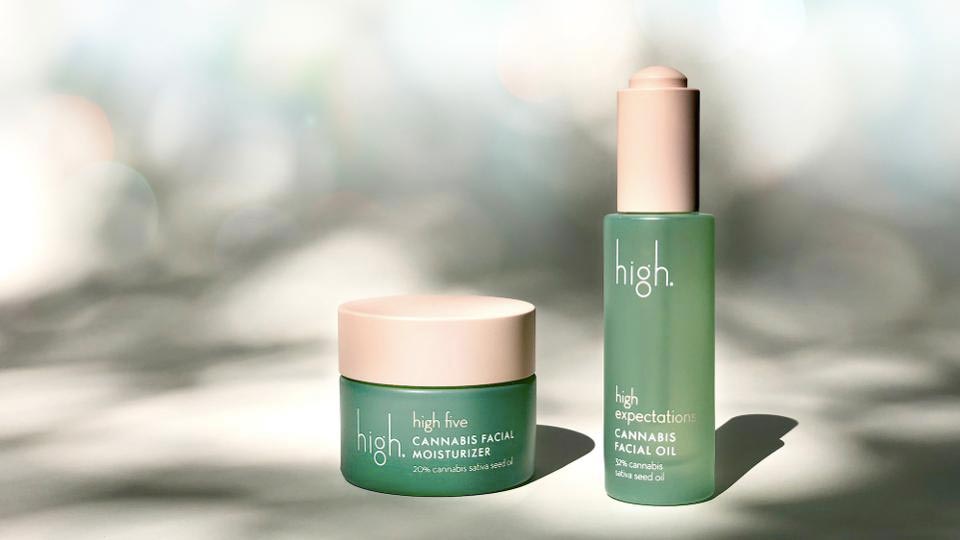 Dvě zelené sklenice kosmetiky značky High s nápisy Cannabis Facial Moisturizer a Cannabis Facial Oil