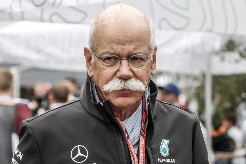 Šéf Mercedesu Dieter Zetsche s brýlemi a bílým knírem v bundě s logem Mercedes-AMG Petronas