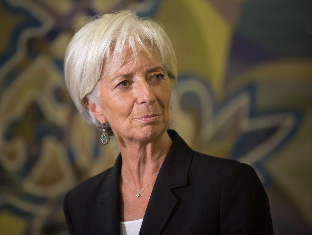 Christine Lagarde s bílými vlasy v černém saku, v pozadí rozostřená barevná mozaika