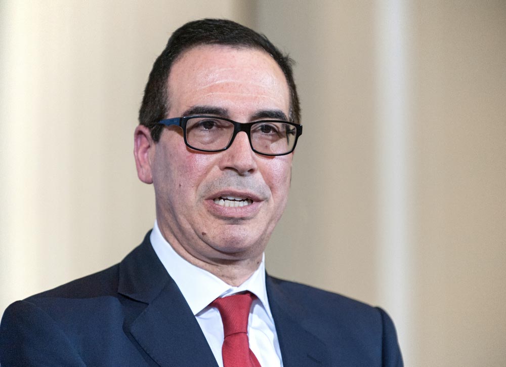 Steven Mnuchin v brýlích, tmavém obleku a červené kravatě během projevu