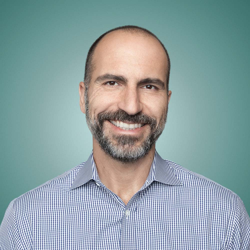 Dara Khosrowshahi, šéf Uberu, usmívající se v kostkované košili na zeleném pozadí