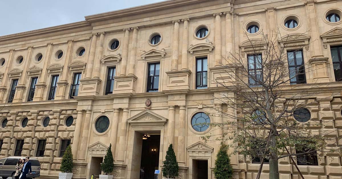 Budova v evropském historizujícím stylu s pilastry a kulatými okny na kampusu společnosti