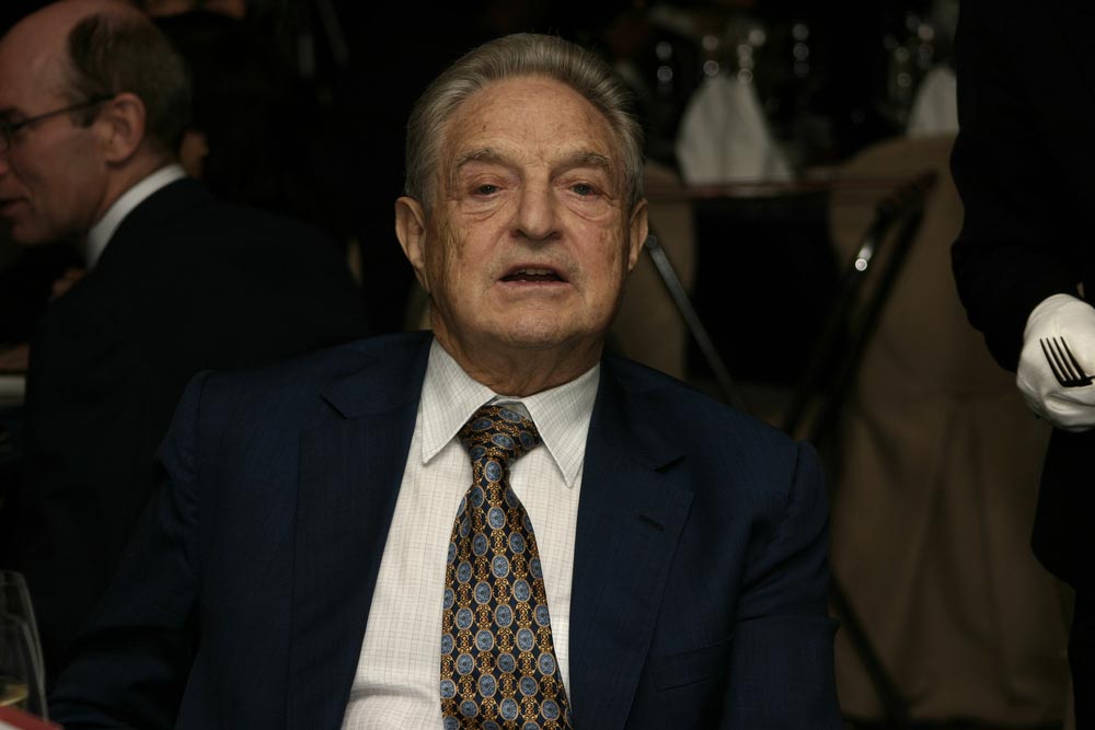 Financník George Soros v tmavém obleku se vzorovanou kravatou na společenské akci