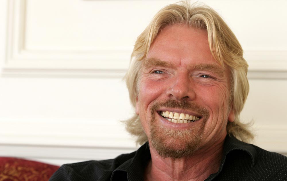 Usmívající se muž se světlými vlasy a plnovousem v tmavé košili - Richard Branson