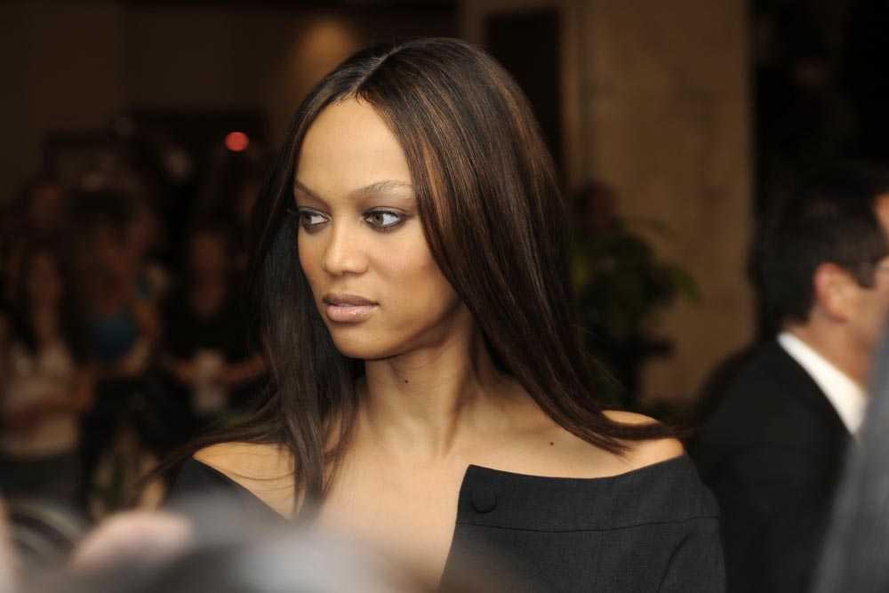Tyra Banks s rovnými vlasy v černých šatech s odhalenými rameny na veřejné akci